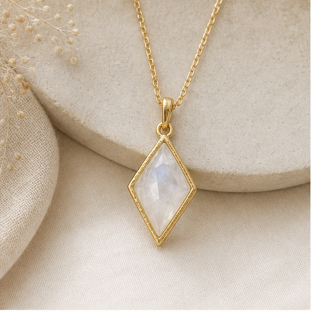 Gold moonstone pendant necklace photographed on warm linen and stone